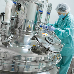 a worker in a green protective suit handling a stainless steel machinery