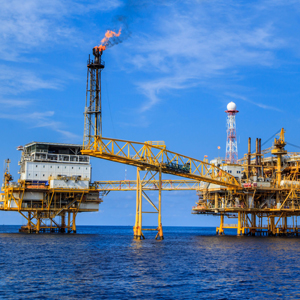 a yellow oil rig in the middle of the ocean with a fire burning at the tip of the tower