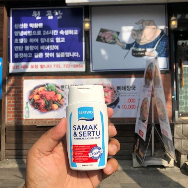 a picture of a hand holding the Sertwo Liquid Clay 250ml in front of a pork restaurant in Korea